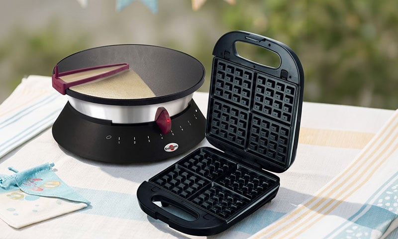 Crêpière électrique et gaufrier ouvert posés sur une table.